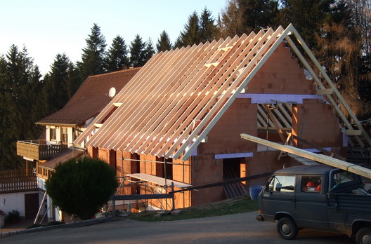 Ein fertig errichteter Dachstuhl auf einem Rohbau aus Backsteinen