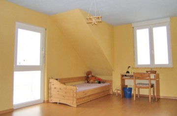 Kindertisch, Stuhl und Bett passen im großen Dachraum mit Dachgaube
